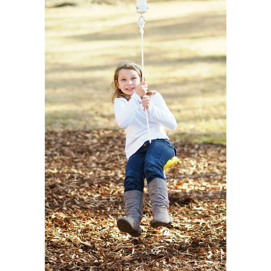 Child modeled by a girl on a rope swing suspended from an outdoor beam, swinging over a mulch ground area in a park setting