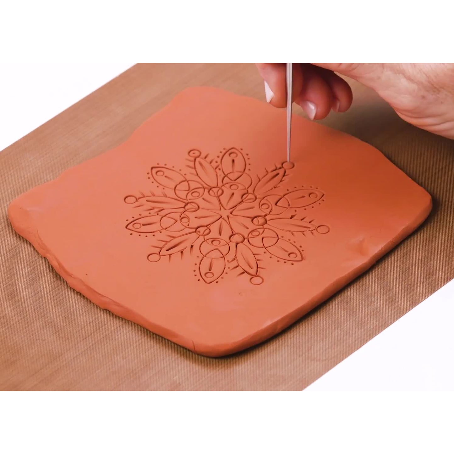 Original Sculpey Terra Cotta clay being carved with a tool to create a mandala design