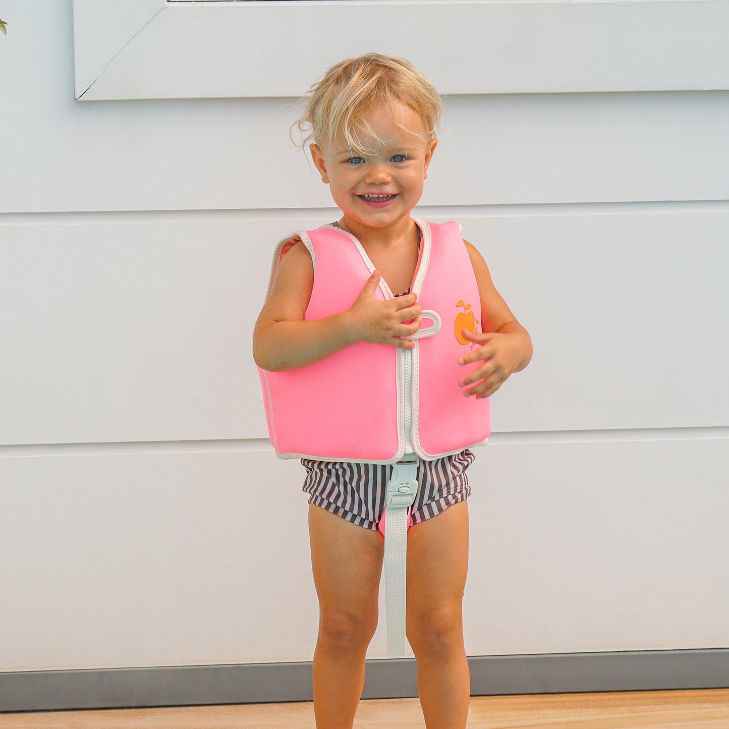 Sunnylife Poppy Peach Float Vest in neon pink with white trim, worn by toddler