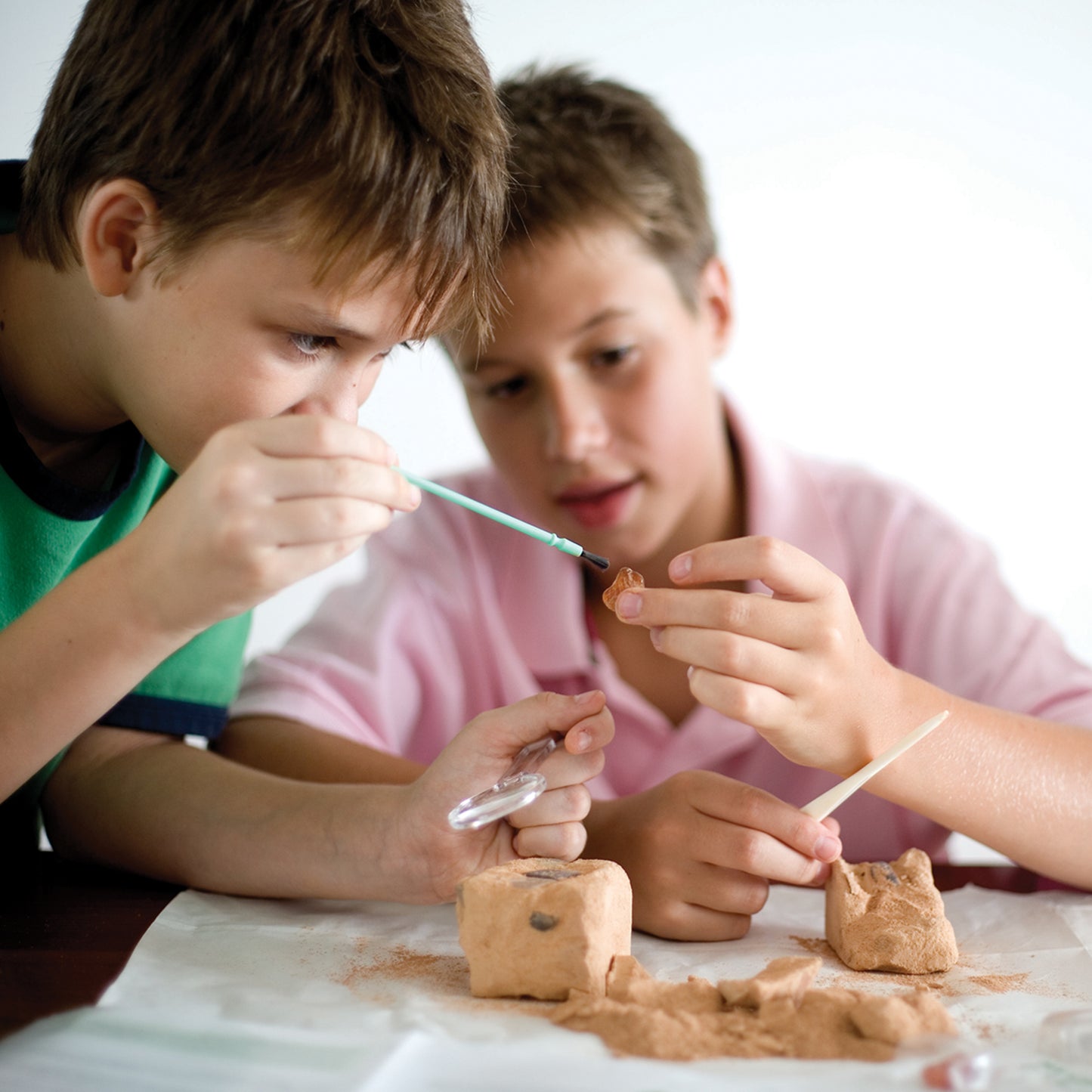 Two children using tools to excavate crystals from a plaster block with the 4M KidzLabs Crystal Mining Kit