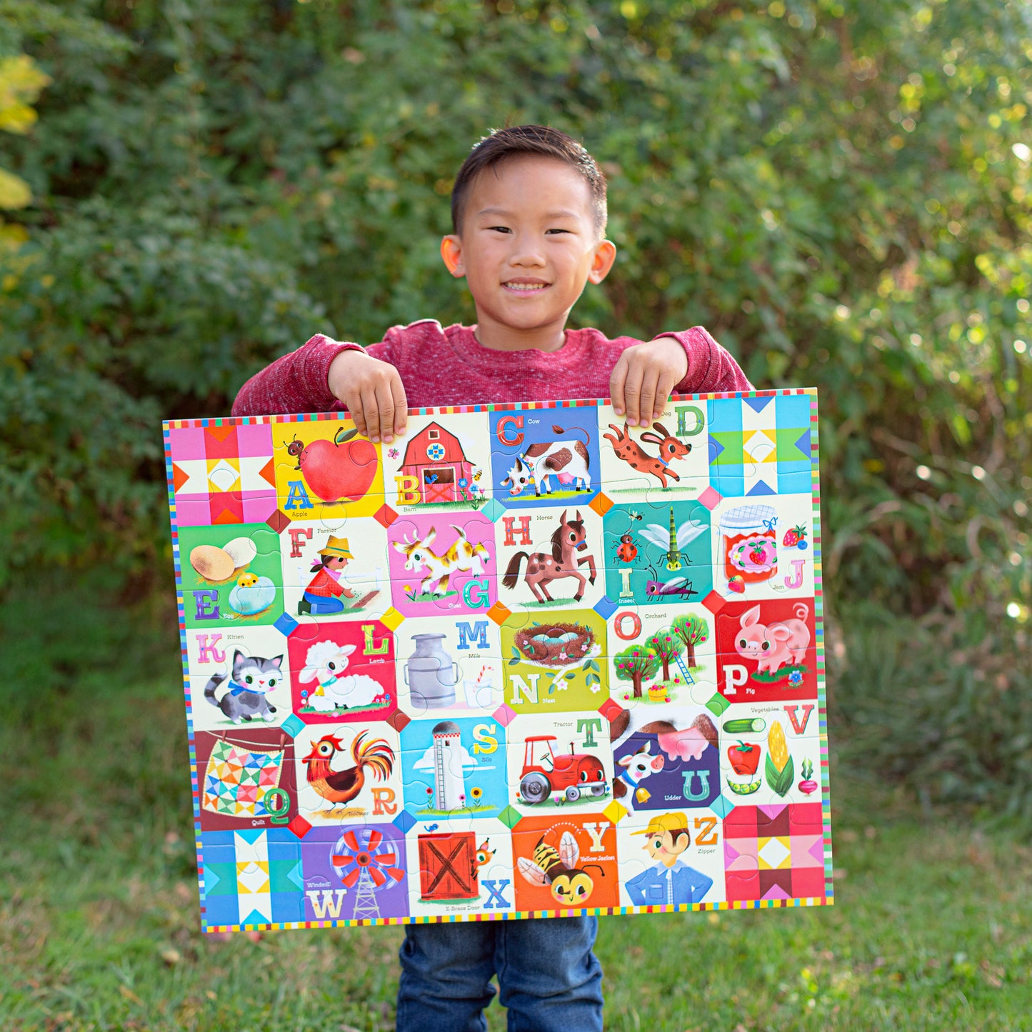 Child holding colorful 36 piece My Farm Alphabet puzzle with letters and farm animals on green background