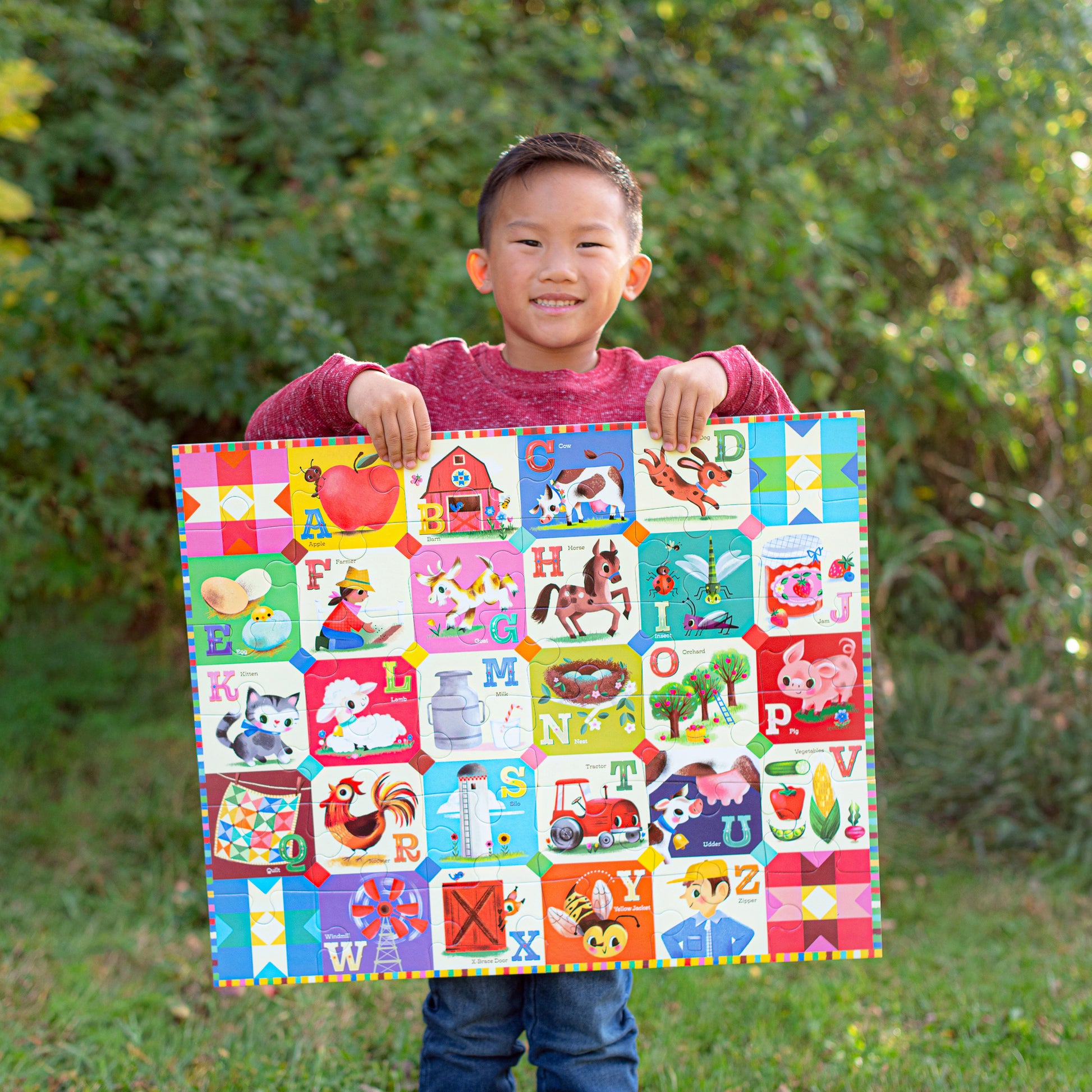 Child holding colorful 36 piece My Farm Alphabet puzzle with letters and farm animals on green background