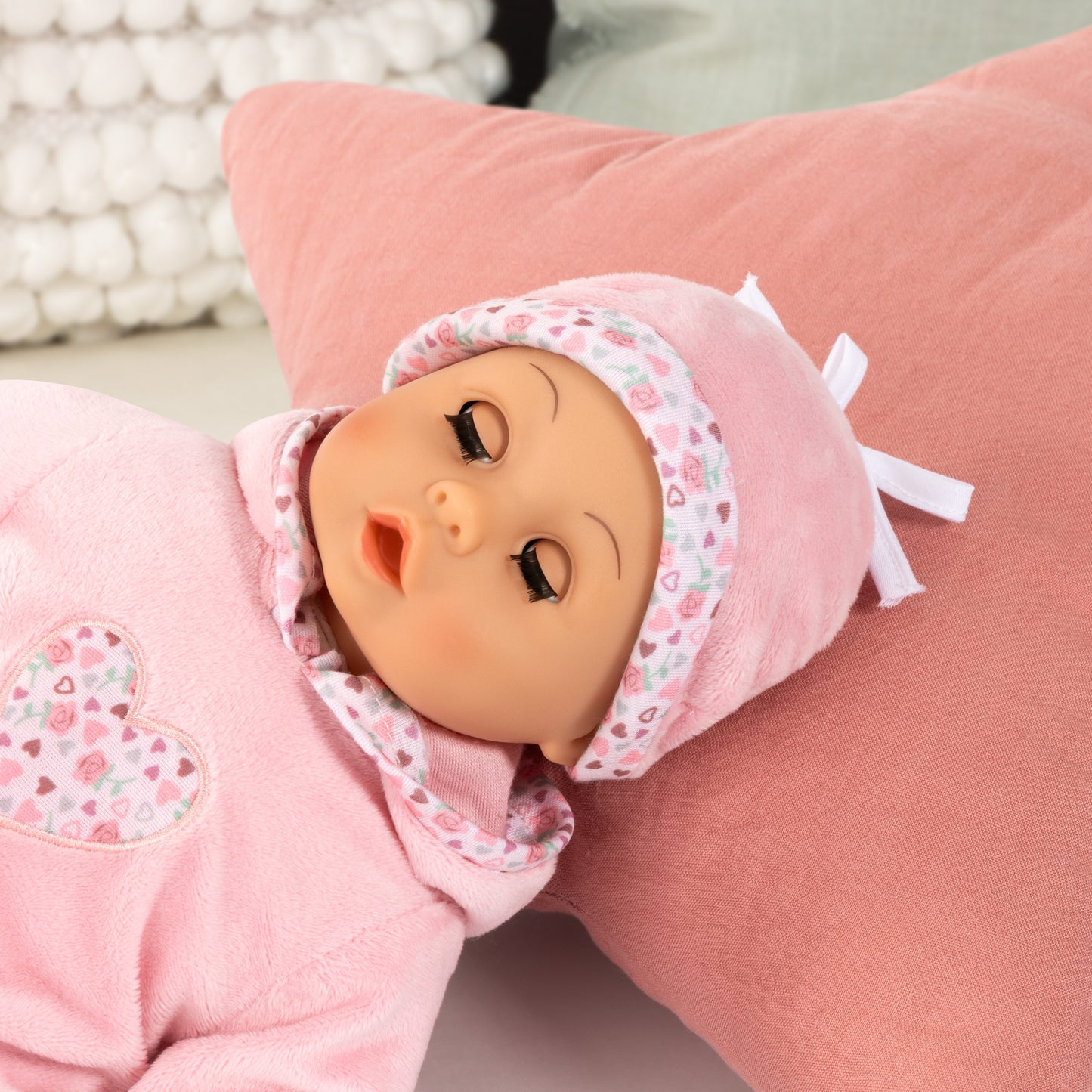 First Words Baby Doll 15-Inch pink with hearts pattern, wearing bonnet, with closed eyes