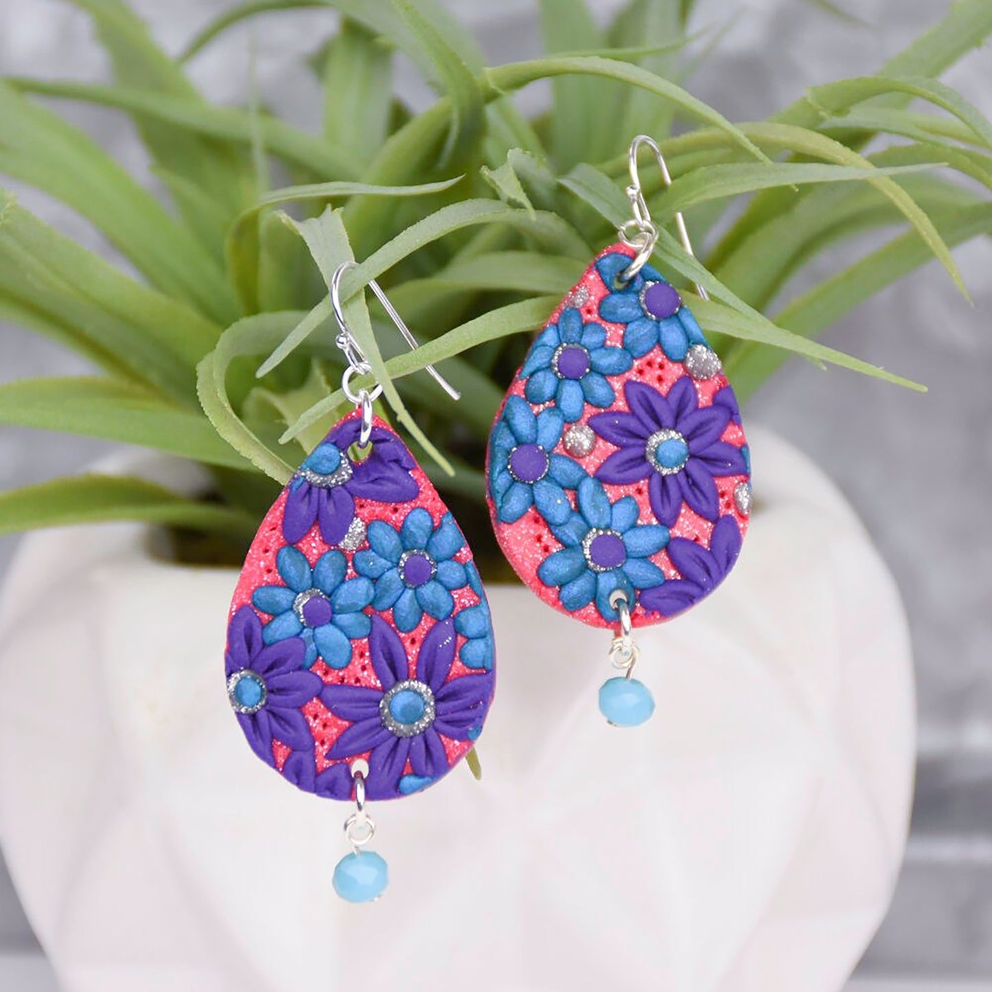 Colorful teardrop earrings with blue, purple, and coral floral patterns and dangling beads