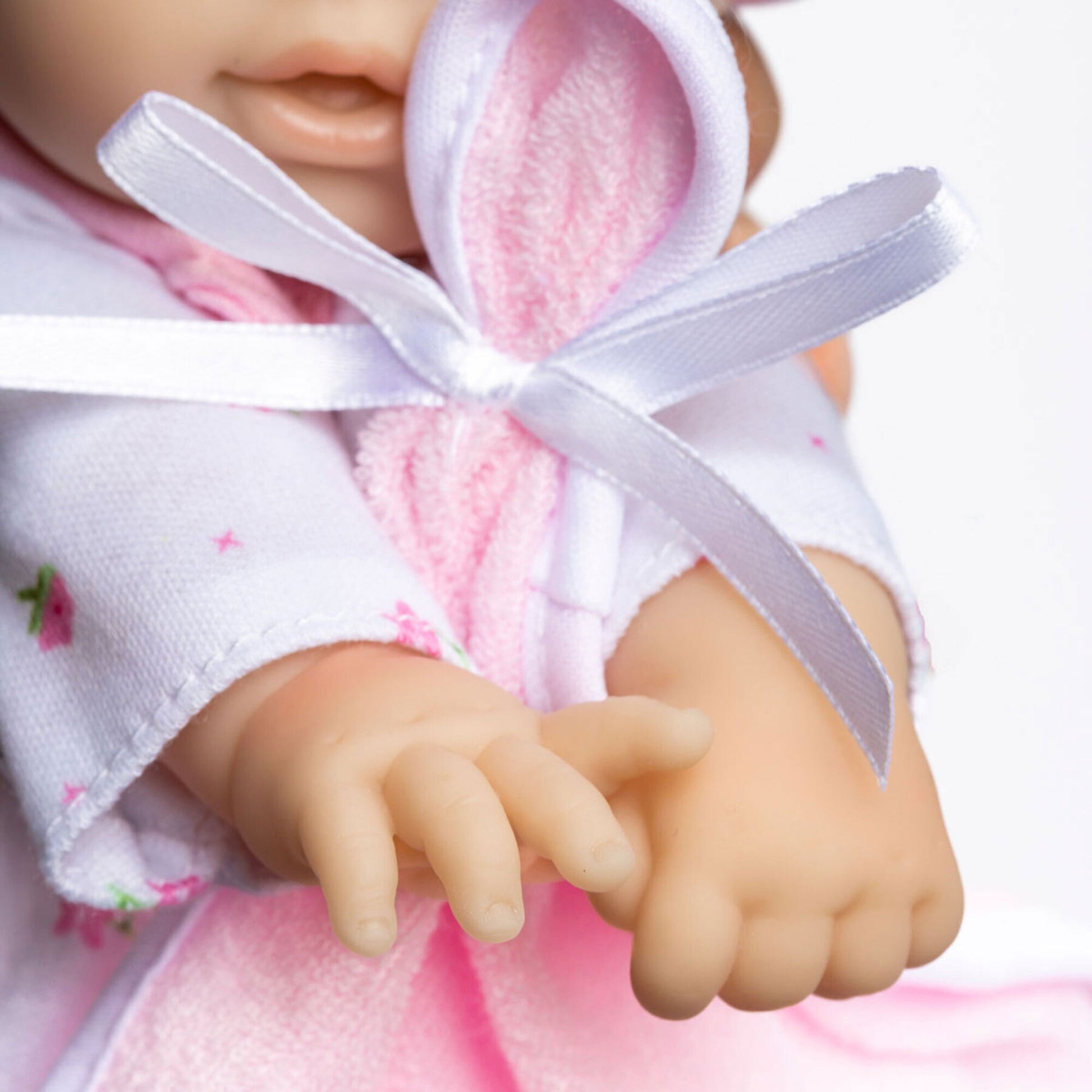 JC Toys La Baby Asian doll in pink outfit with white blanket and pacifier