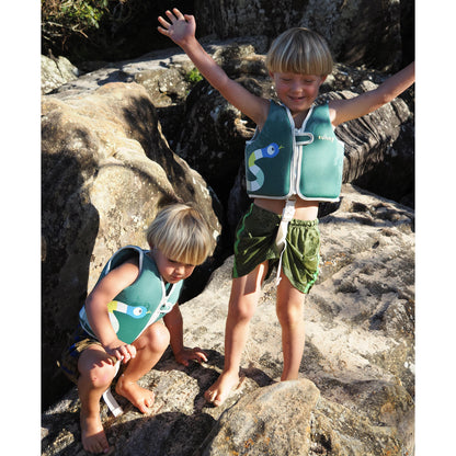 Sunnylife Into The Jungle Float Vest in green with fish design, worn by child at beach