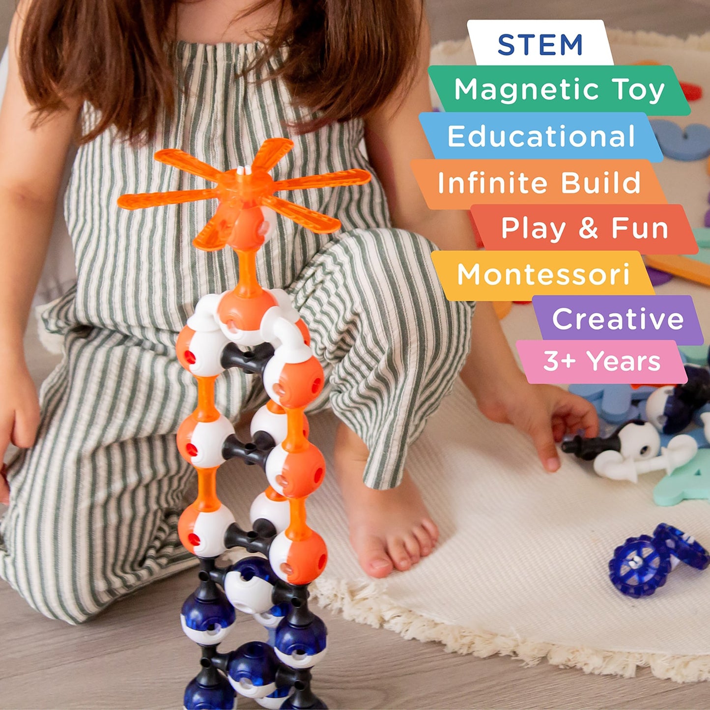 KUB Planet magnetic building set with orange and blue pieces being held by child, showing connected spheres and conne...
