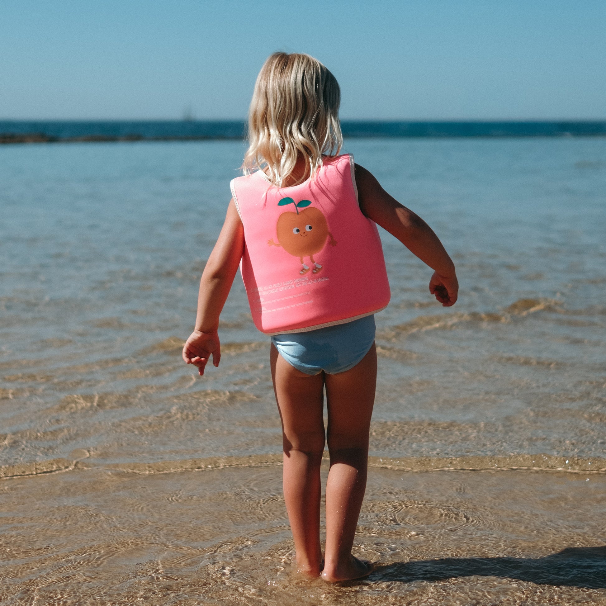 Neon pink Float Vest Poppy the Peach for ages 3-6 worn by child at beach