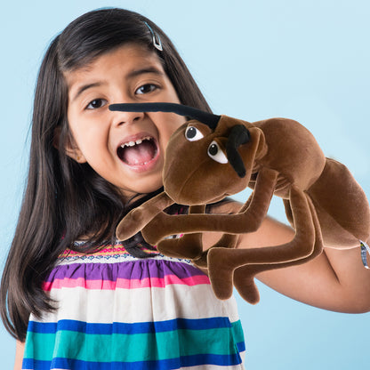 Living Puppets Addie The Ant brown hand puppet with movable mouth, held by smiling child wearing colorful striped shirt