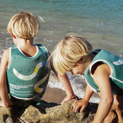 Sunnylife Into The Jungle Float Vest in teal with adjustable safety strap, worn by child at beach