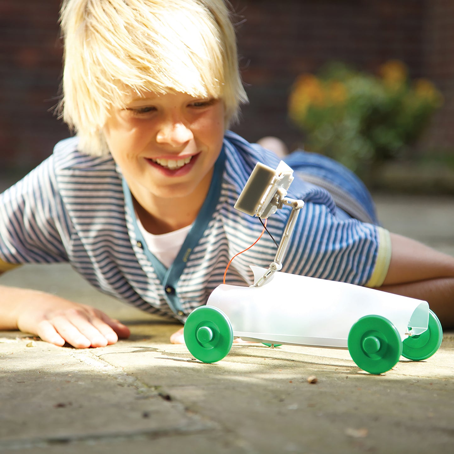 4M Green Science Solar Rover DIY kit with green wheels, child playing outdoors