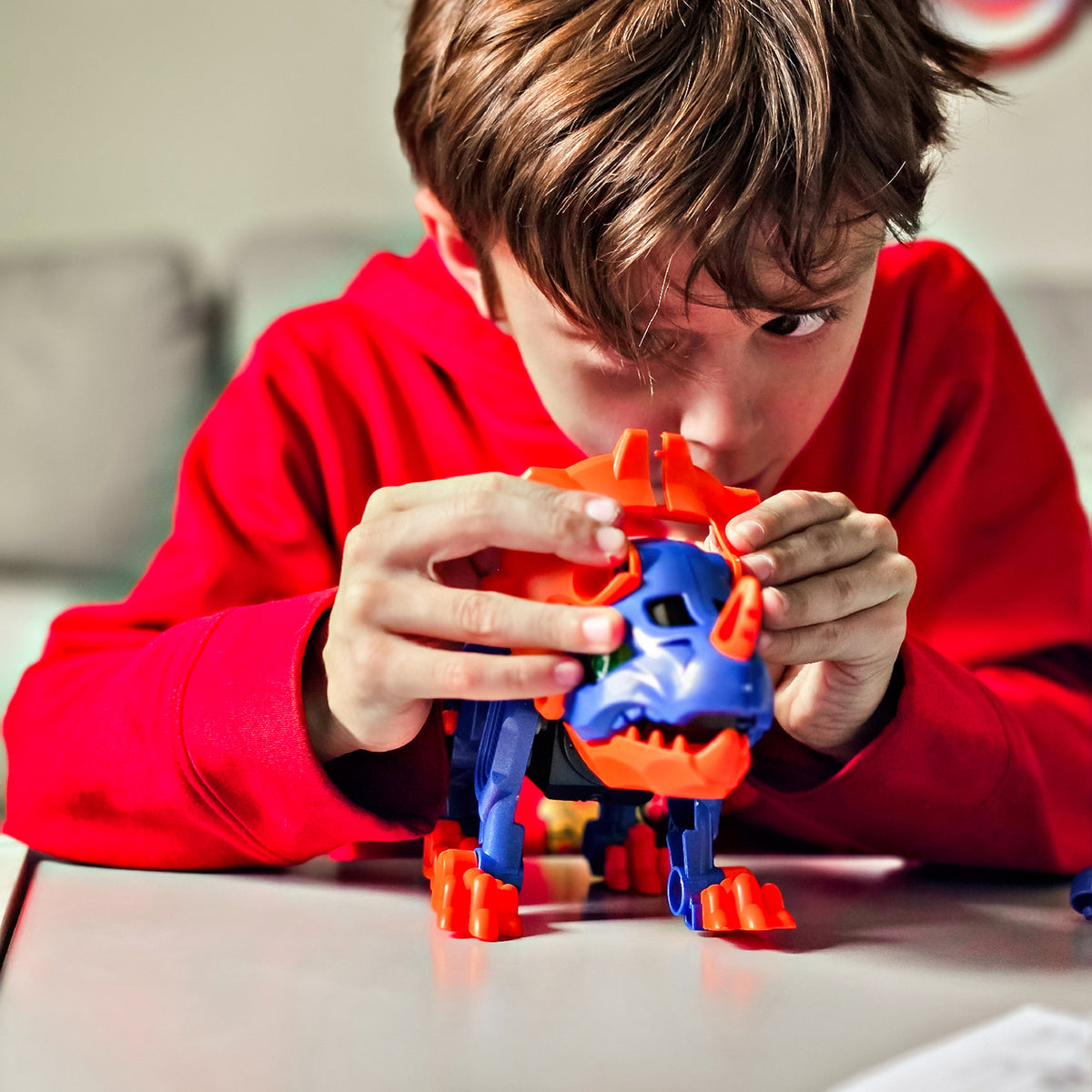 Child assembling blue and orange Teach Tech Triceratops Robot STEM toy