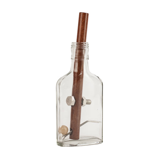 Clear glass bottle with wooden dowel rod inside and metal bolts and wooden ball puzzle pieces, brain teaser game on plain background