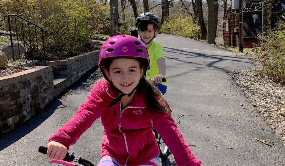 girl and boy with helmets safely ride their bikes