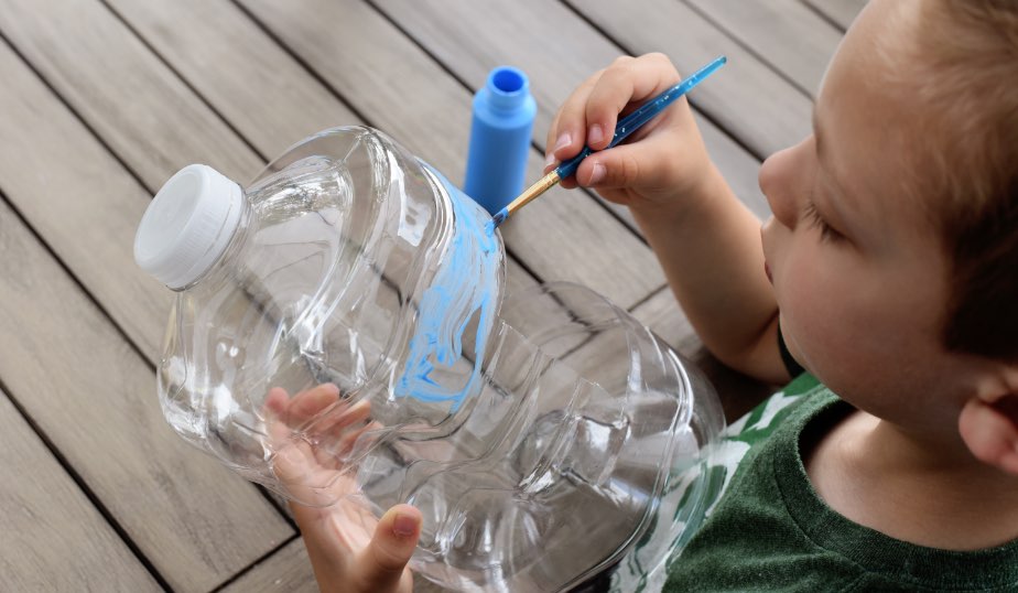 child painting a plastic water jug for the diy bird feeder activity for kids